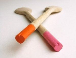 A pair of crossed, wooden spoons with pink and orange heart shaped ends.